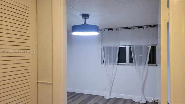 a view of a room with wooden floor and a chandelier fan