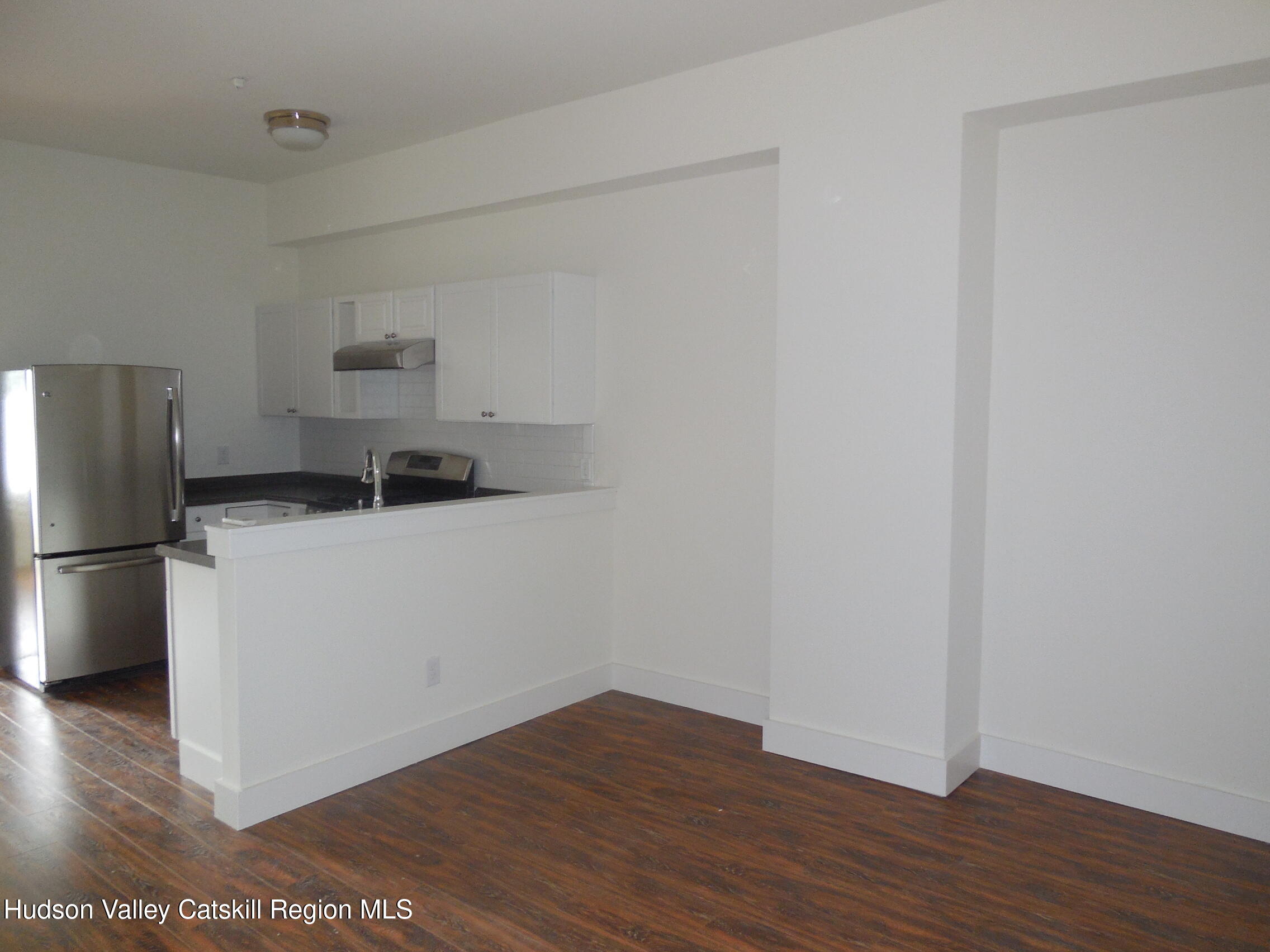 431 Warren Street, Unit 2 Hudson, NY 12534 - Photo 2 of 6 a kitchen with a refrigerator and wooden floor