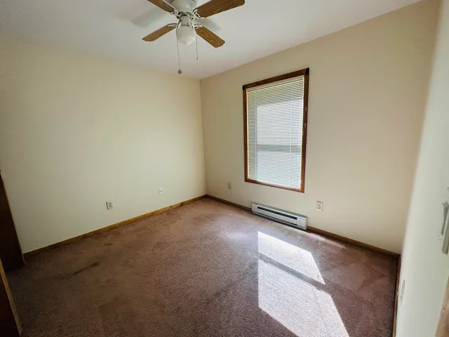 an empty room with a window and ceiling fan