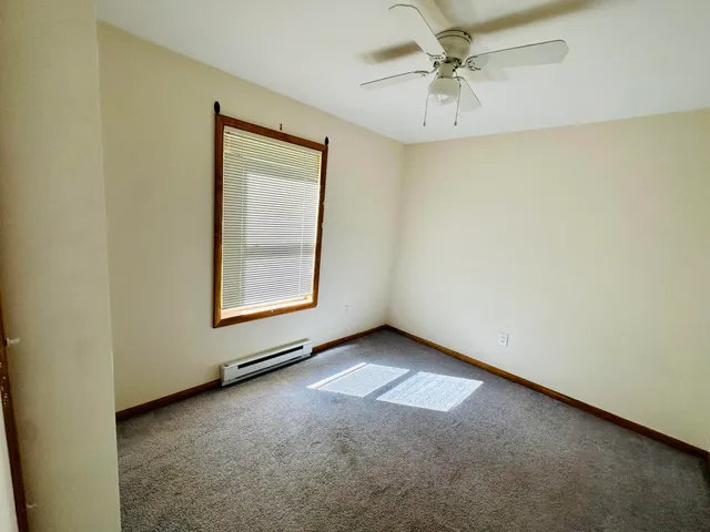 an empty room with windows and fan