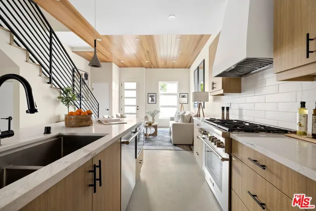 a kitchen with stainless steel appliances granite countertop a sink a stove and a wooden floors