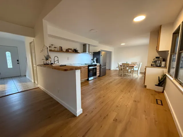 a view of a kitchen with kitchen island a counter top space a sink a stove and wooden floor