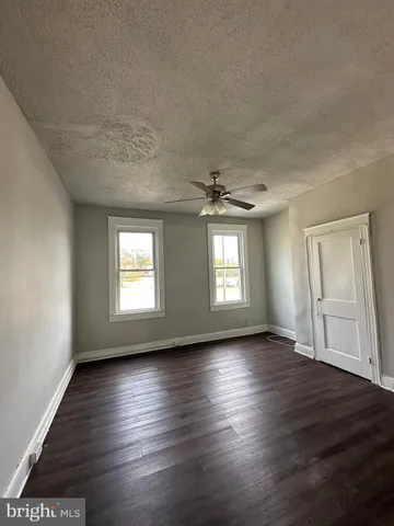 an empty room with wooden floor chandelier and windows