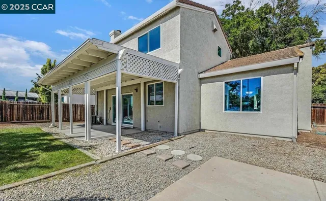 a view of a house with small yard plants and large tree