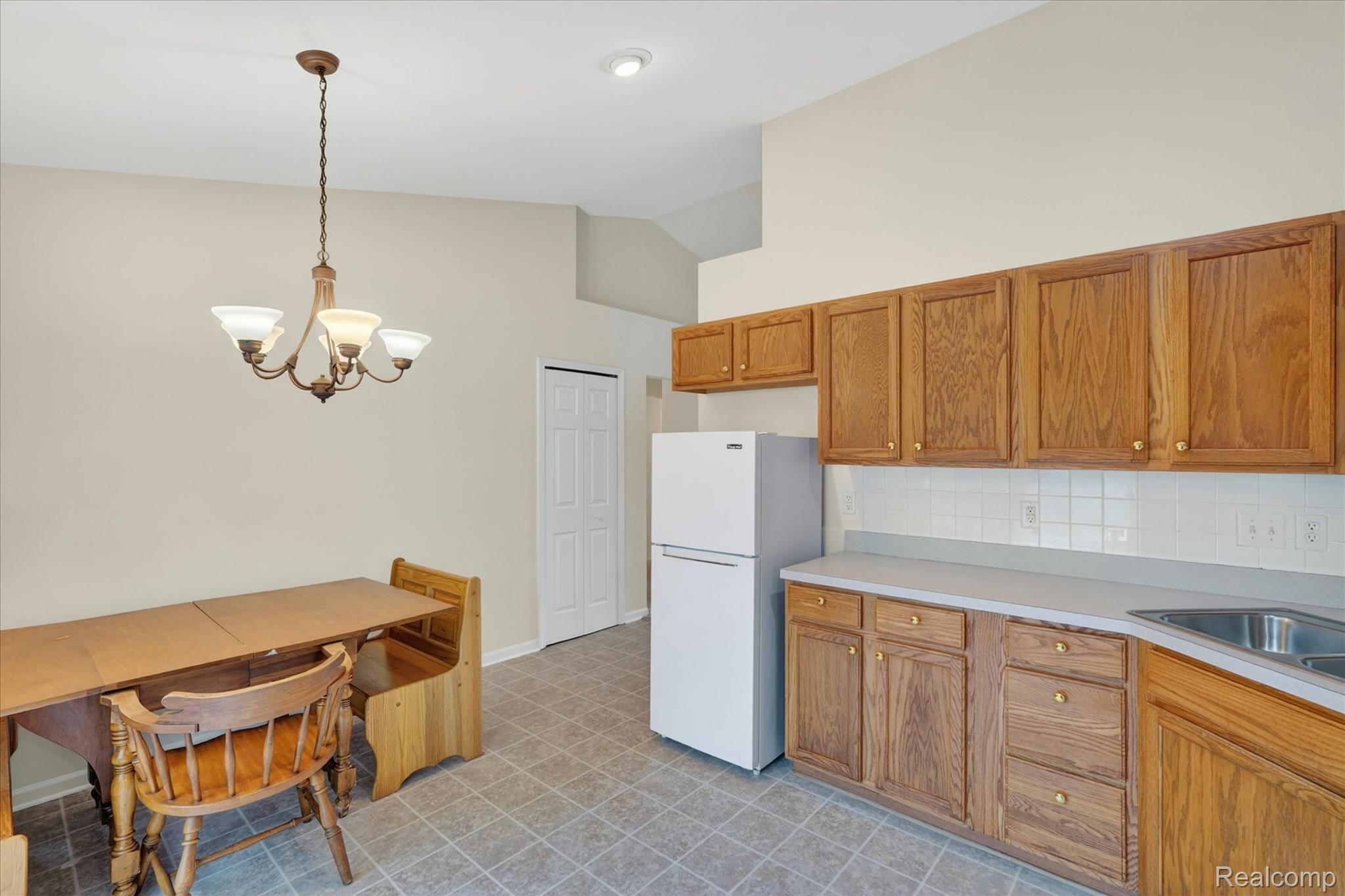 1607 Cedarwood Drive Flushing, MI 48433 - Photo 11 of 27 Kitchen with wood finish cabinets, light countertops, freestanding refrigerator, suspended lighting, and vaulted ceiling