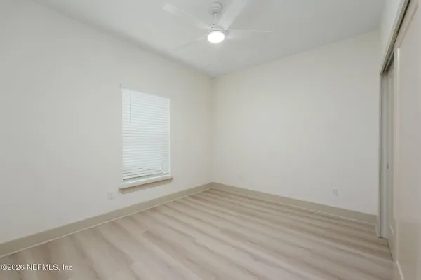 an empty room with wooden floor and fan