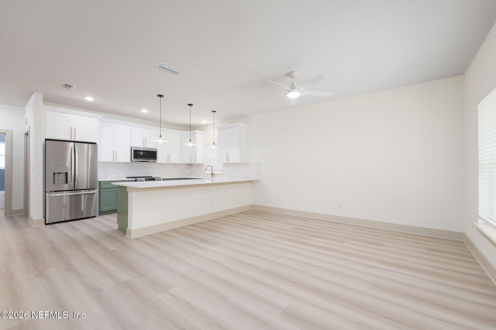 716 West 6th Street St. Augustine, FL 32084 - Photo 4 of 28 a large white kitchen with kitchen island a sink a stove a refrigerator and white cabinets with wooden floor