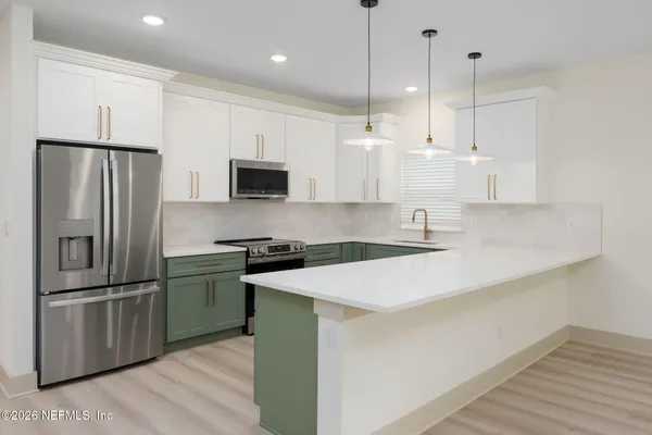 a kitchen with stainless steel appliances granite countertop a refrigerator a sink a stove and a refrigerator