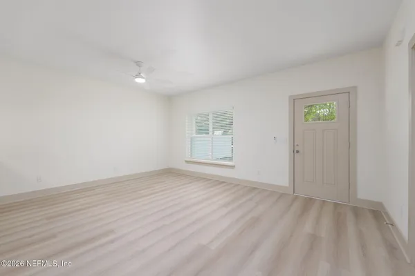 a view of an empty room with wooden floor and a window