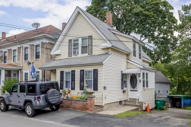 a view of a white house with large windows and lawn chairs under an umbrella
