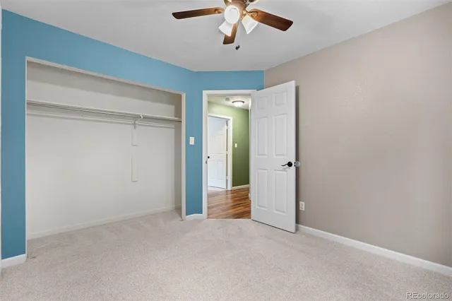 an empty room with a ceiling fan and carpet