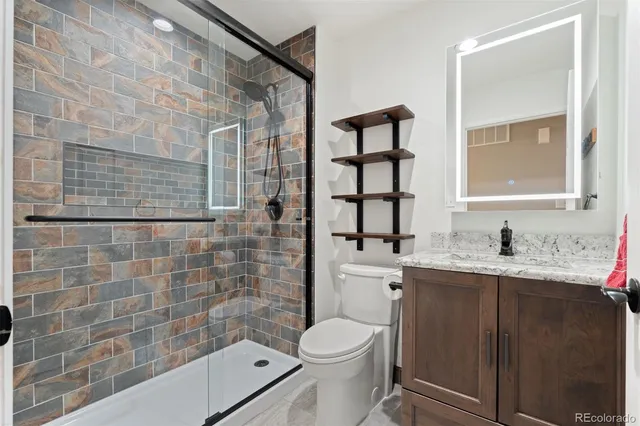 a bathroom with a granite countertop sink a toilet and shower