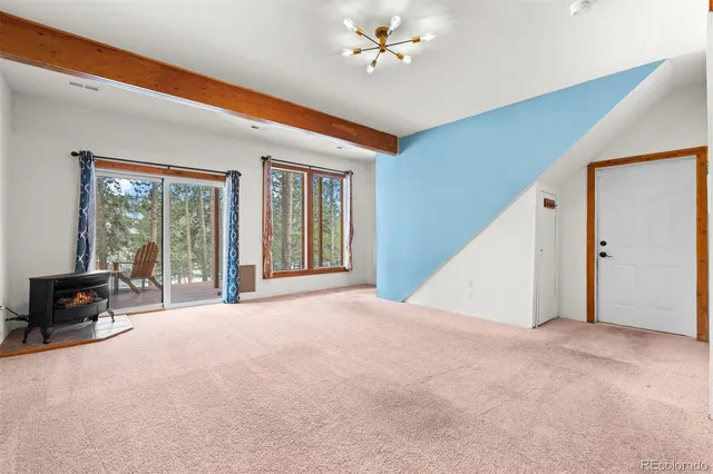 a view of an empty room with window and chandelier fan