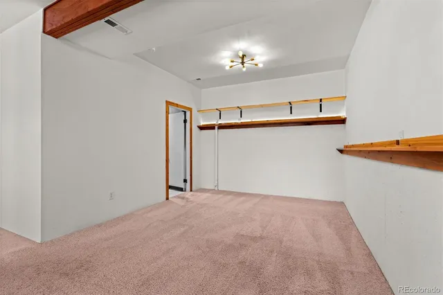 a view of an empty room with a chandelier fan