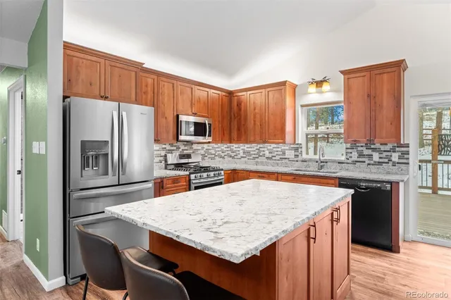 a kitchen with stainless steel appliances granite countertop a table chairs sink refrigerator and microwave