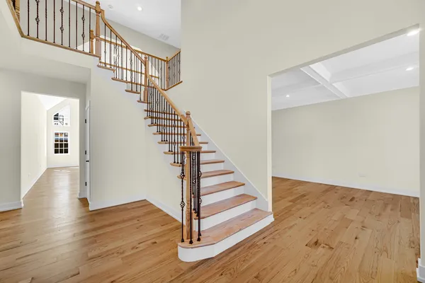 a large kitchen with stainless steel appliances kitchen island granite countertop a stove a sink a refrigerator and white cabinets with wooden floor