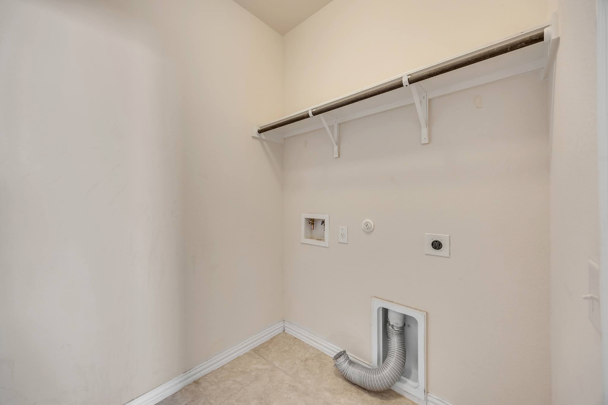 7212 Vail Ridge Street Austin, TX 78744 - Photo 14 of 26 A dedicated laundry space provides practical utility with a convenient hanging rod and upper shelf.