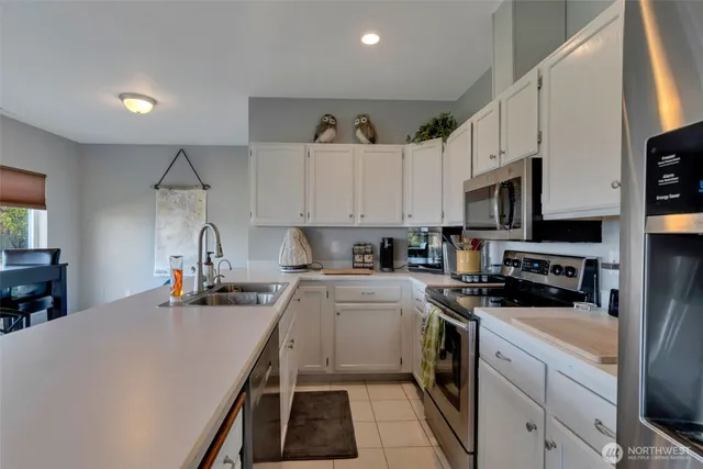 a kitchen with stainless steel appliances a refrigerator a stove a sink a dining table and chairs