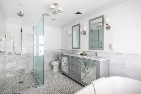 a bathroom with a granite countertop sink a toilet a mirror and shower