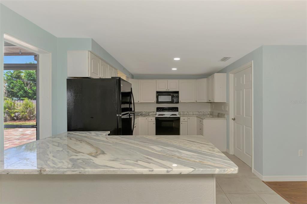 2490 Eleventh Street Englewood, FL 34224 - Photo 12 of 49 a large kitchen with white cabinets and stainless steel appliances