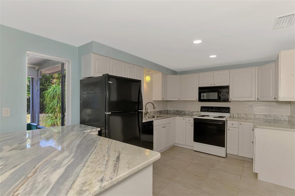 2490 Eleventh Street Englewood, FL 34224 - Photo 16 of 49 a kitchen with stainless steel appliances granite countertop a refrigerator stove and microwave