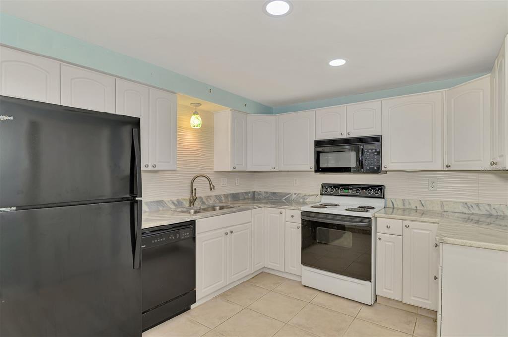 2490 Eleventh Street Englewood, FL 34224 - Photo 18 of 49 a kitchen with white cabinets and white appliances