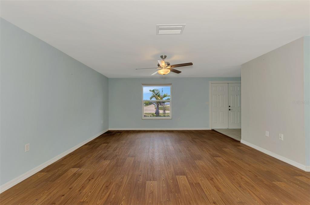 2490 Eleventh Street Englewood, FL 34224 - Photo 5 of 49 an empty room with wooden floor chandelier fan and windows