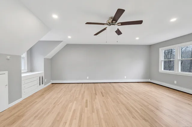 an empty room with wooden floor windows and ceiling fan