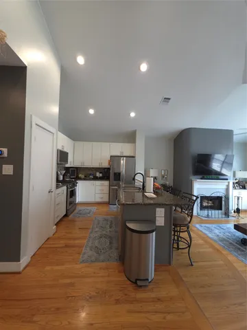 a large kitchen with kitchen island a sink a counter and chairs
