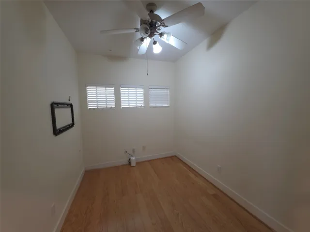 an empty room with a window and a fan