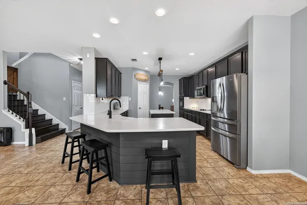 a kitchen with stainless steel appliances kitchen island granite countertop a table chairs and a refrigerator