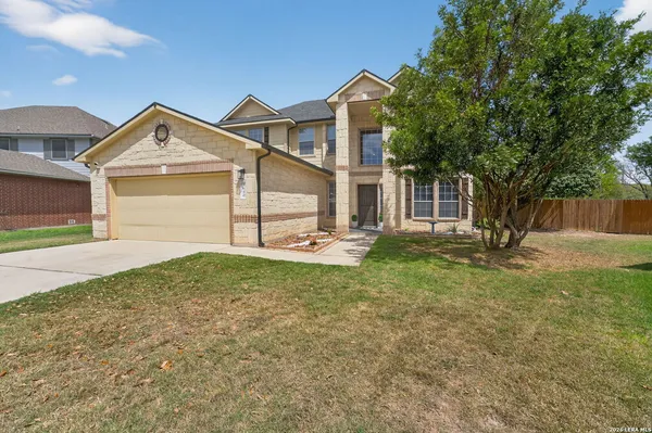 a view of a house with a yard and large tree