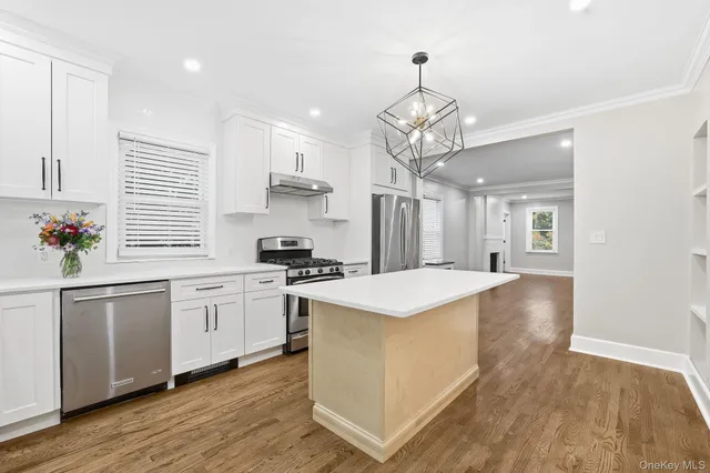 a kitchen with stainless steel appliances a white stove top oven a sink dishwasher and white cabinets with wooden floor