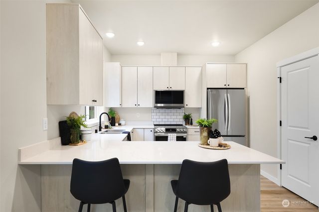 a kitchen with stainless steel appliances a dining table chairs a refrigerator and cabinets