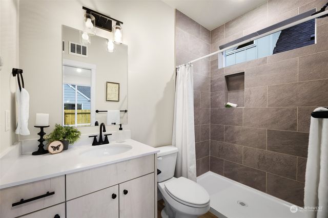 a bathroom with a sink a toilet a mirror and shower