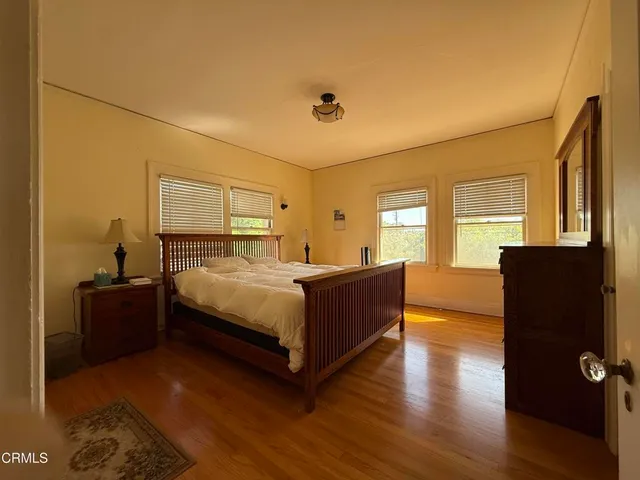 a spacious bedroom with a bed and wooden floor