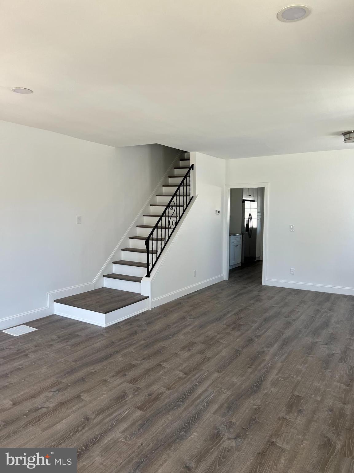 a view of an empty room with wooden floor and stairs