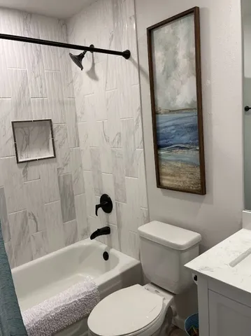 a white toilet sitting next to a bathroom sink and tub