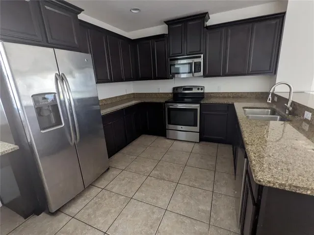 a kitchen with granite countertop a refrigerator and a sink