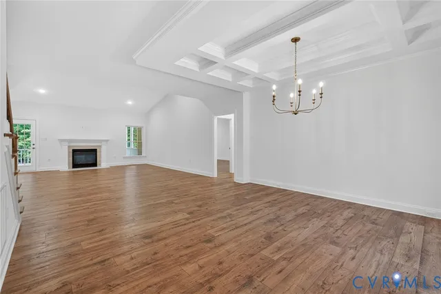 a view of empty room with wooden floor and kitchen view