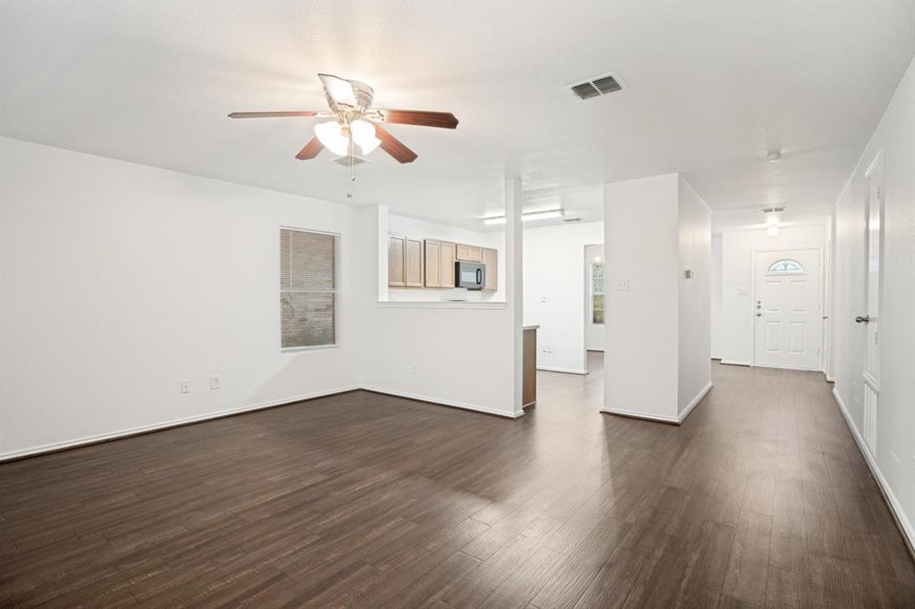 16701 Windthorst Way Fort Worth, TX 76247 - Photo 3 of 12 a view of an empty room with wooden floor and a ceiling fan