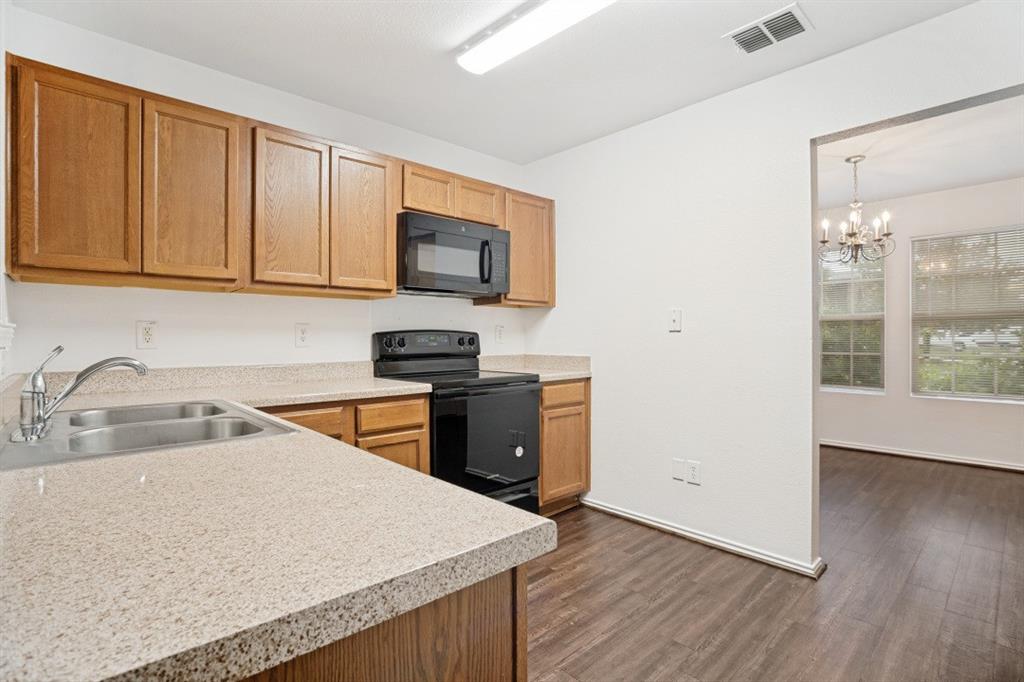 16701 Windthorst Way Fort Worth, TX 76247 - Photo 5 of 12 a kitchen with stainless steel appliances granite countertop a sink stove and microwave