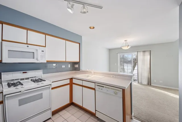 a kitchen with granite countertop white cabinets sink and white appliances