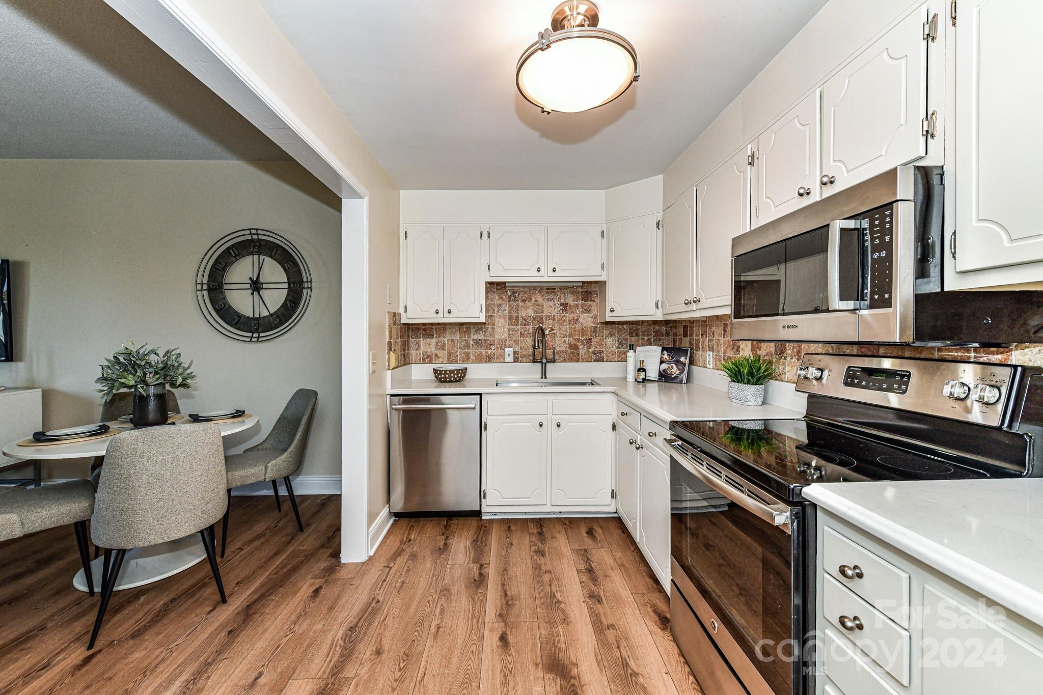 1300 Reece Road, Unit 415 Charlotte, NC 28209 - Photo 15 of 32 a kitchen with stainless steel appliances granite countertop a stove a sink dishwasher and white cabinets with wooden floor