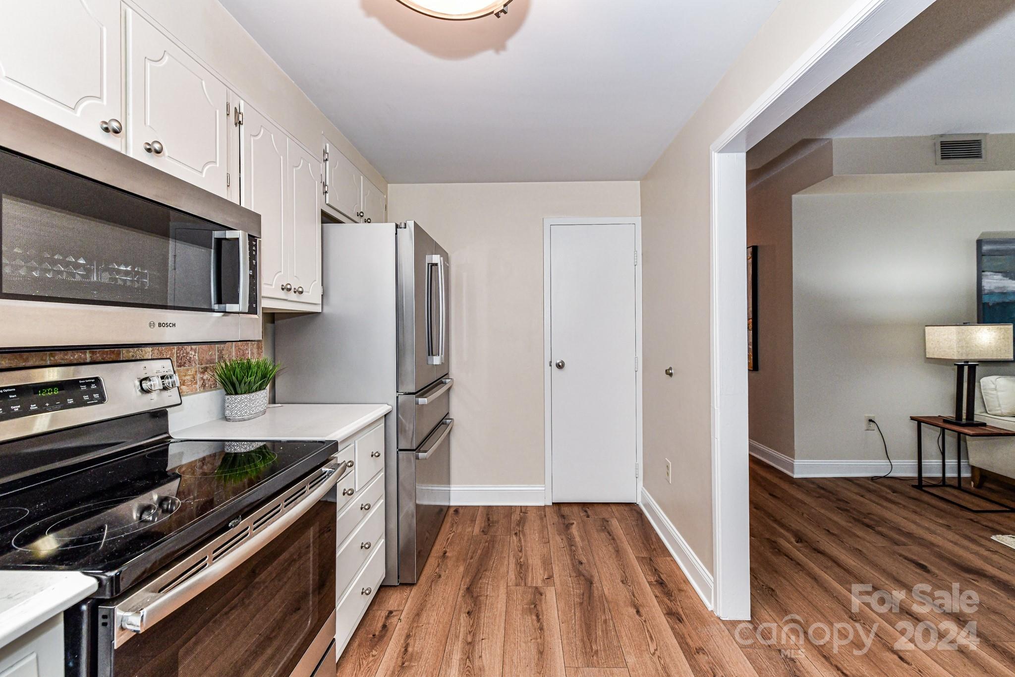 1300 Reece Road, Unit 415 Charlotte, NC 28209 - Photo 16 of 32 a kitchen with wooden floors appliances and cabinets