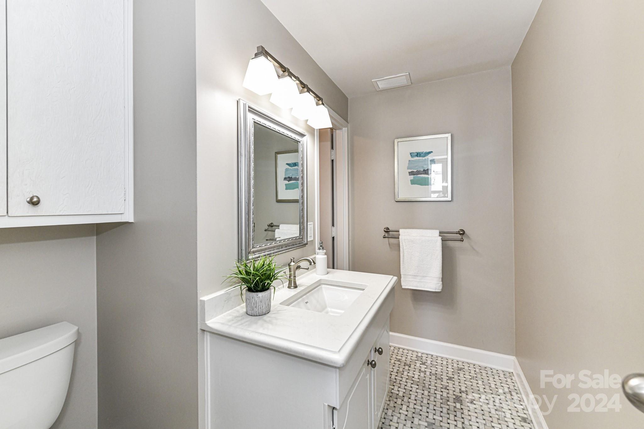 1300 Reece Road, Unit 415 Charlotte, NC 28209 - Photo 25 of 32 a bathroom with a sink a toilet and mirror