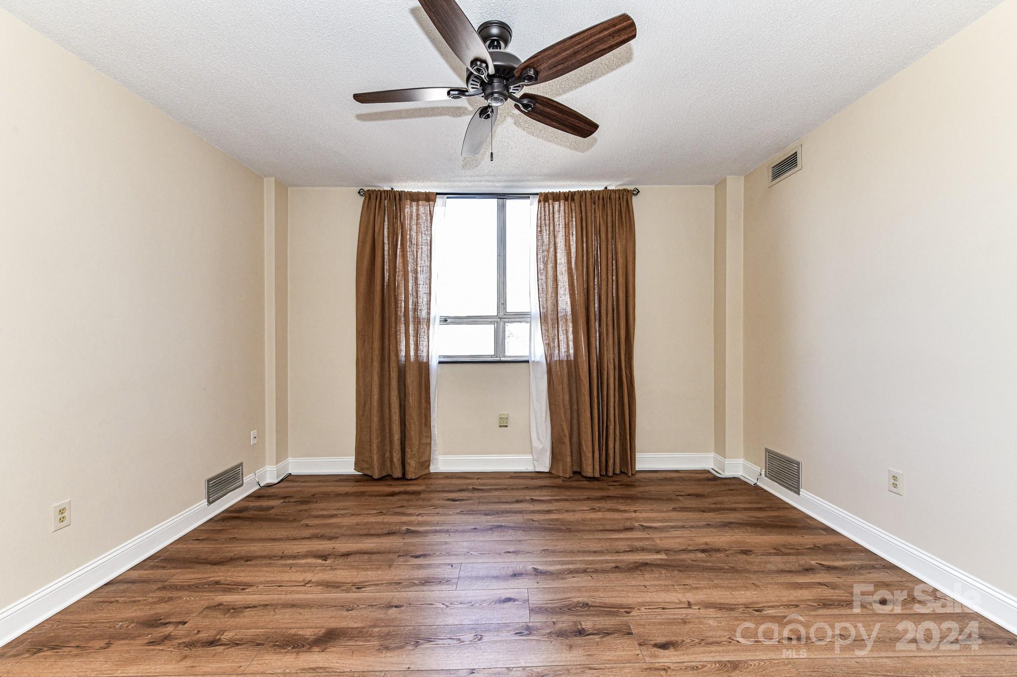 1300 Reece Road, Unit 415 Charlotte, NC 28209 - Photo 26 of 32 an empty room with wooden floor ceiling fan and windows