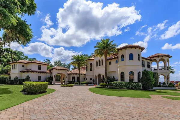 a view of a white house with a big yard plants and large trees