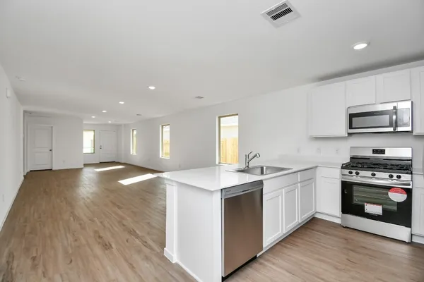 a kitchen with stainless steel appliances granite countertop a stove a sink and a microwave