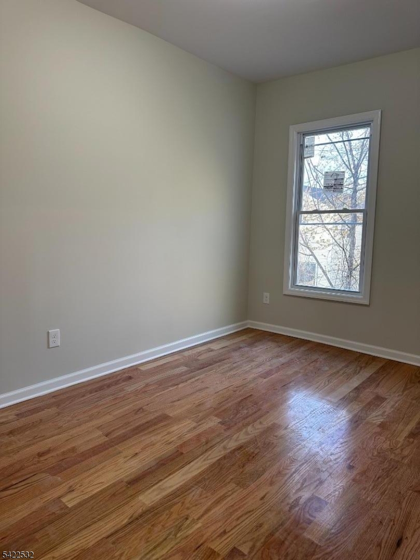 68 Arch Street Paterson, NJ 07522 - Photo 3 of 6 a view of an empty room with wooden floor and a window